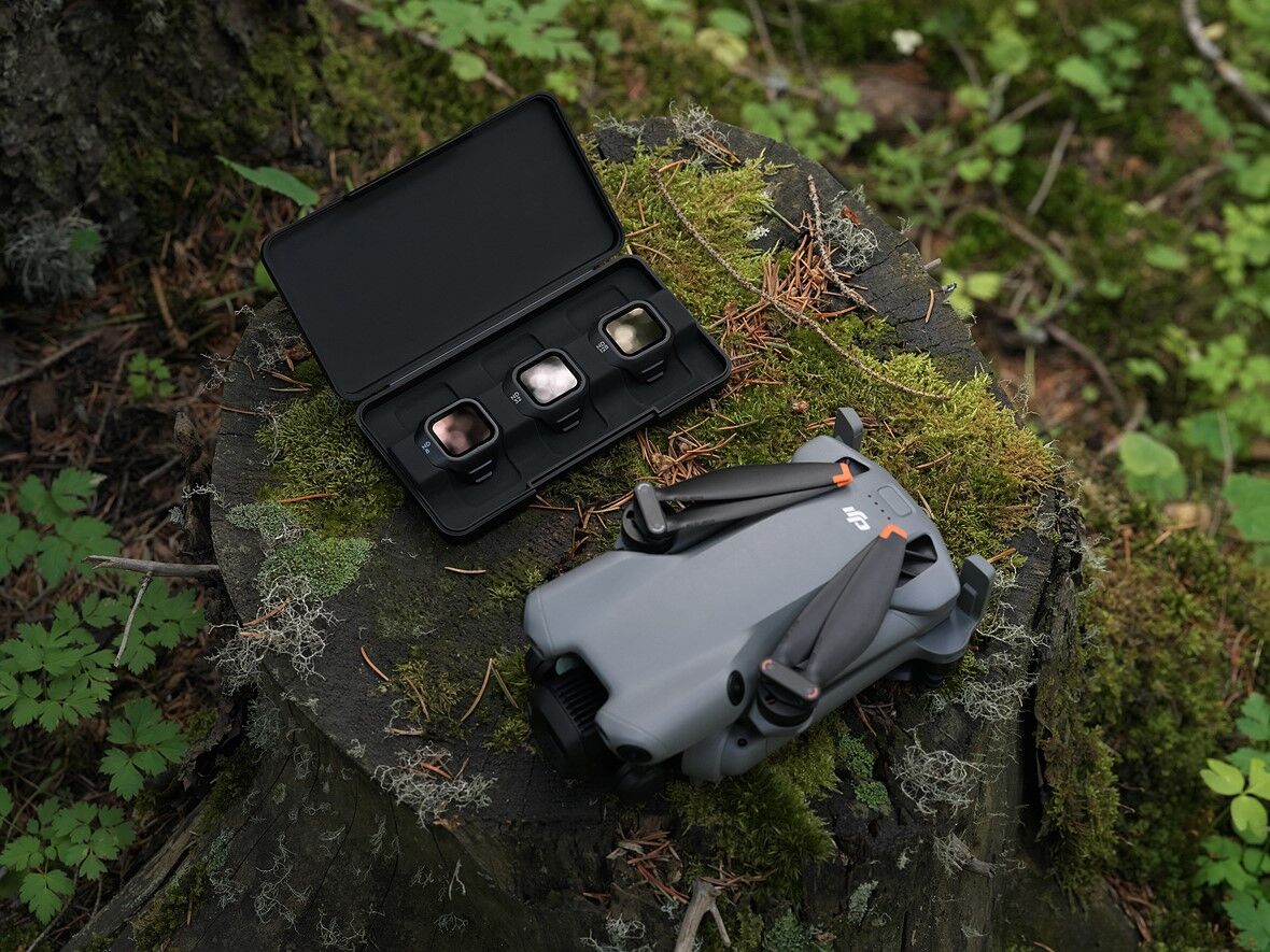 a_case_with_small_filters_and_the_dji_mini_5_pro_are_on_a_moss_covered_stump