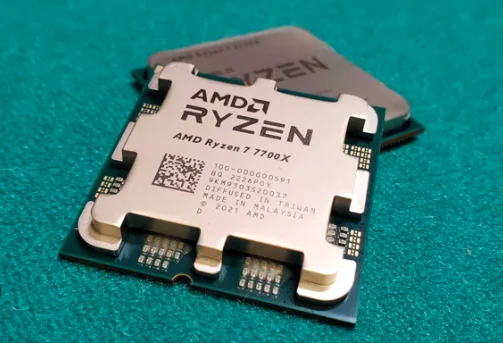 "CPU AMD Ryzen™ 7 7700 là một bộ vi xử lý cao cấp dành cho máy tính để bàn, có thiết kế nhỏ gọn dạng hình vuông, vỏ ngoài bằng kim loại màu bạc với tên sản phẩm được in rõ nét trên bề mặt. Sản phẩm thường được đặt trong hộp đi kèm tản nhiệt AMD Wraith Prism – một quạt làm mát có đèn LED RGB nhiều màu, kiểu dáng mạnh mẽ, hiện đại. Bộ vi xử lý này mang phong cách thiết kế tối giản, gọn gàng, phù hợp với các dàn máy tính hiệu suất cao."