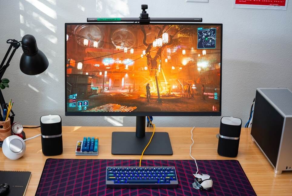 Màn hình 32 inch trên bàn gỗ, hiển thị cảnh đêm trong cyberpunk 2077.