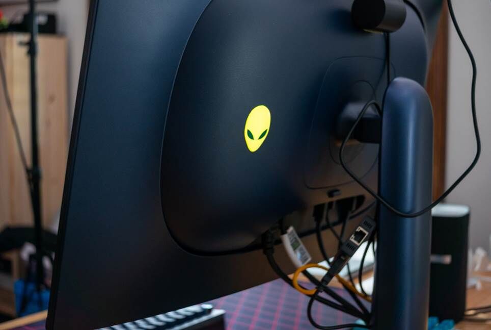 Cận cảnh mặt sau của màn hình chơi game màu xanh navy. Có một logo đầu người ngoài hành tinh phát sáng màu vàng.