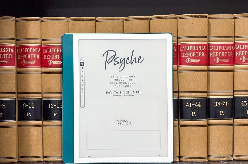 Kindle Scribe trước một chồng sách đặt trên kệ.