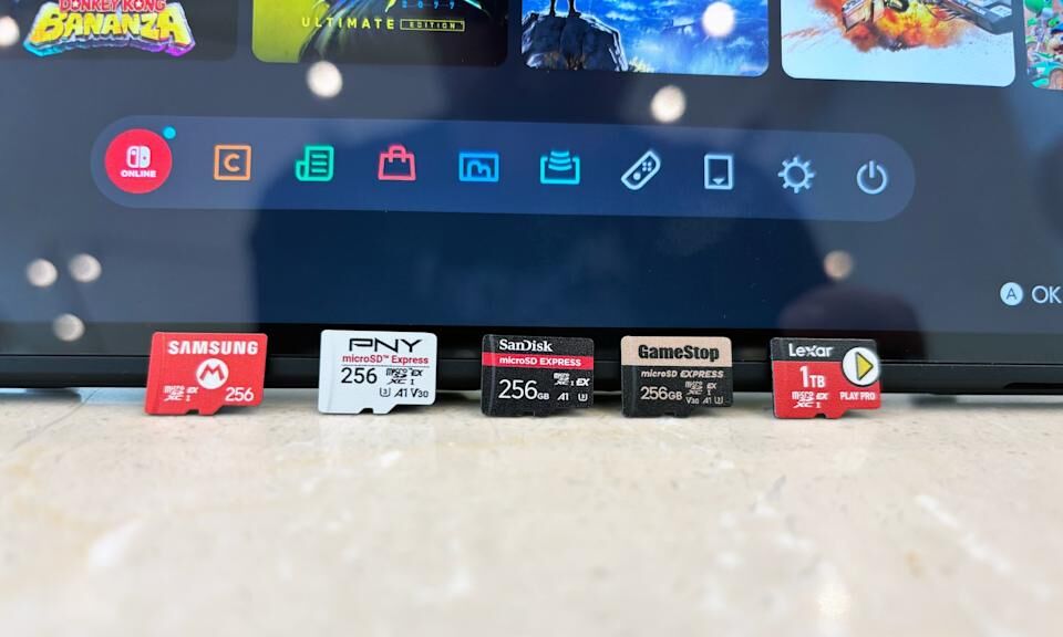 A collection of microSD Express cards sit propped up on a marble table against the display of a Nintendo Switch 2.