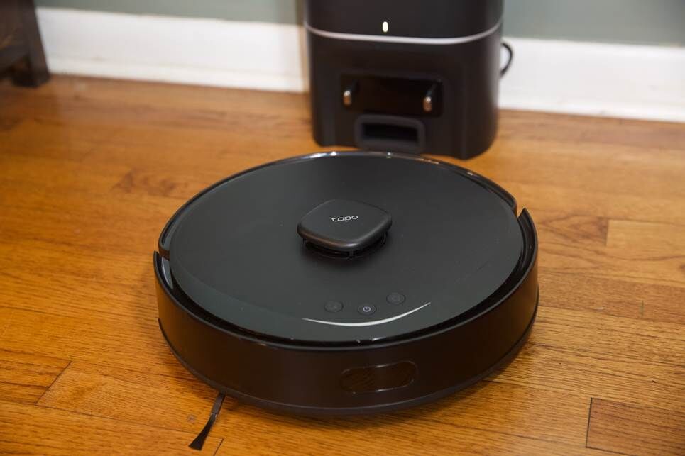 Một robot hút bụi màu đen trên sàn gỗ cứng