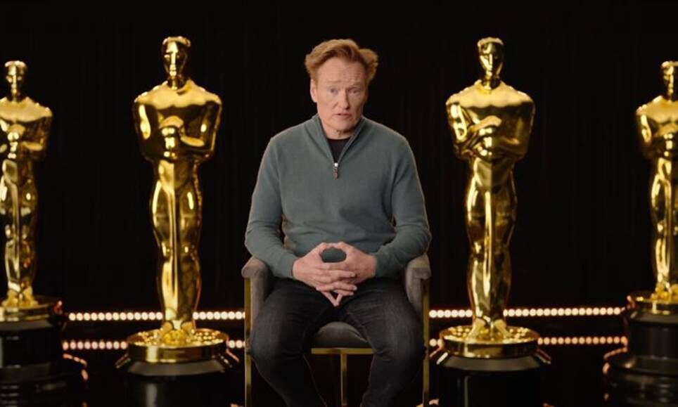 Conan O'Brien ngồi giữa những tượng Oscar khổng lồ.