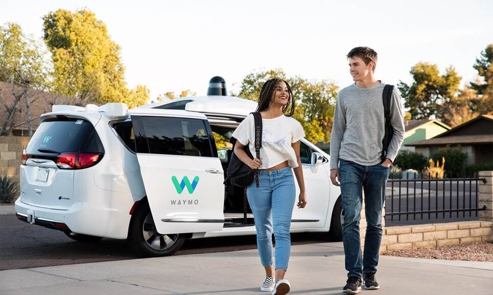 Hai người bước ra khỏi xe taxi Waymo.