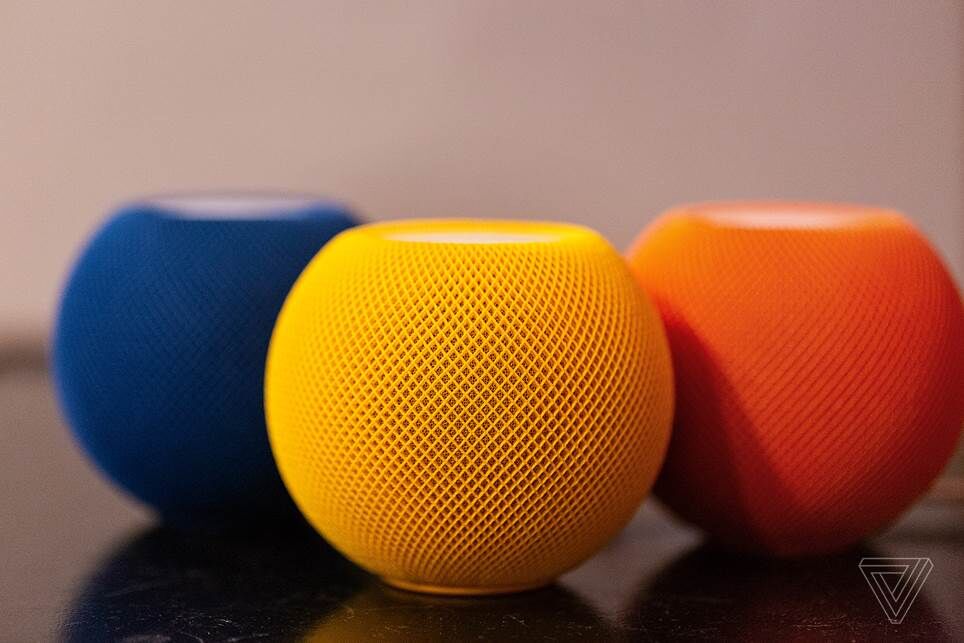 Ba loa thông minh HomePod Mini của Apple đặt trên bàn với nhiều sắc thái khác nhau bao gồm cam, vàng và xanh lam.